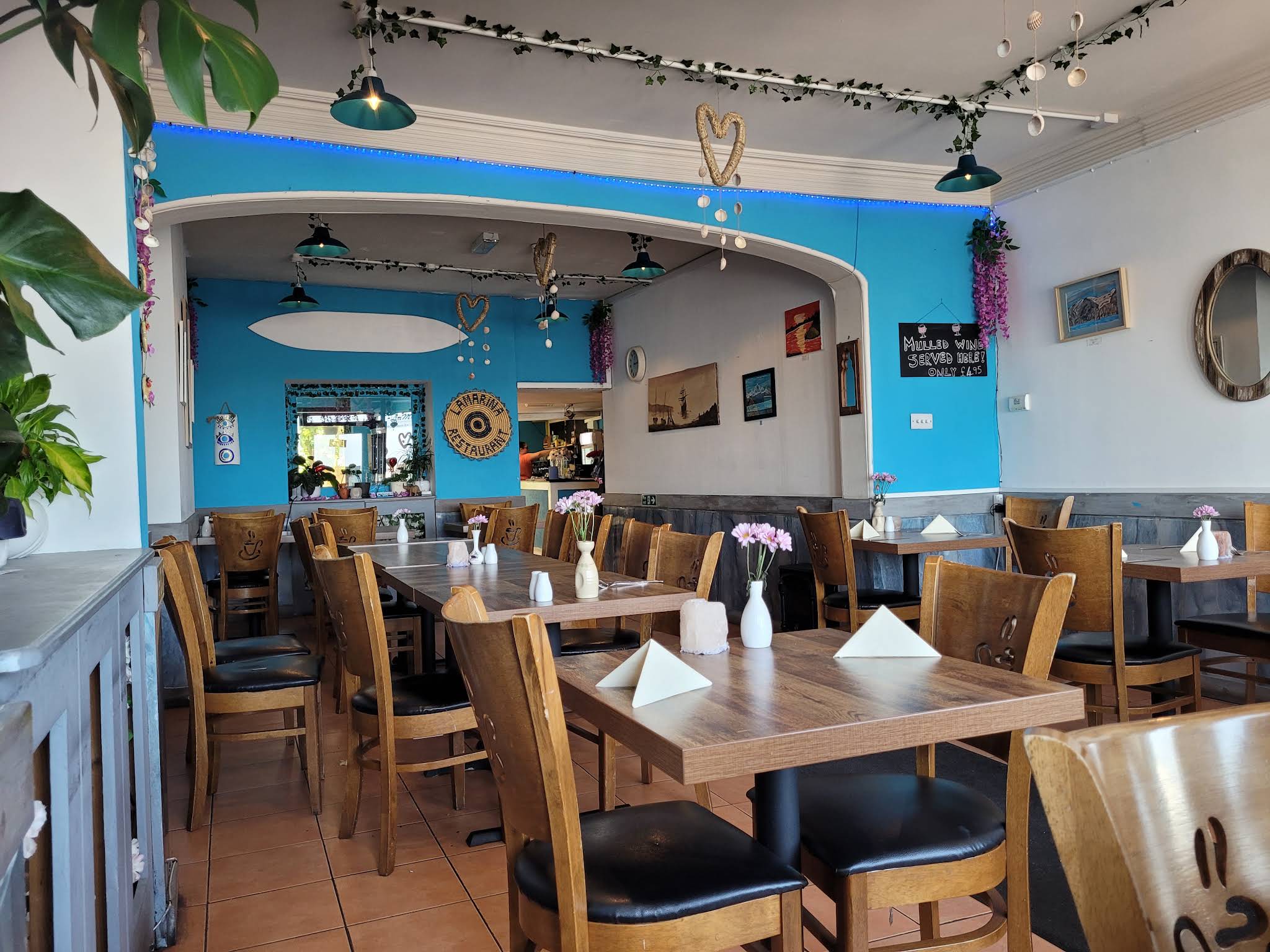 Lamarina restaurant interior with bright blue archways, wood tables, green pendant lights and flowers